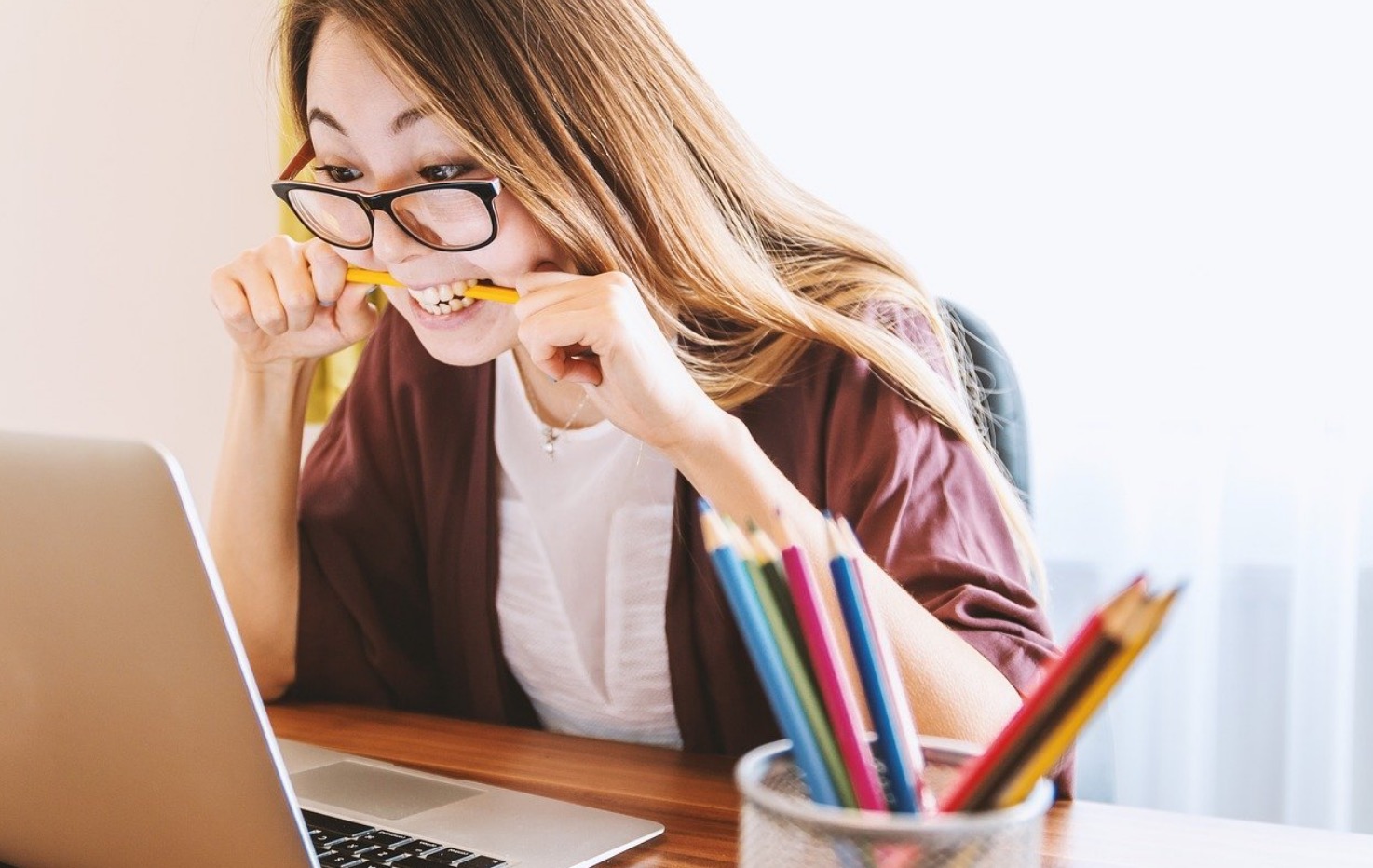 lady biting pencil in fron of computer